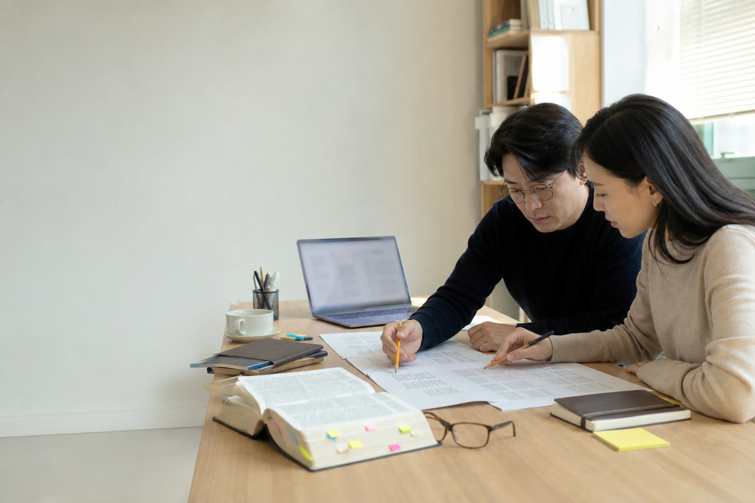 두 편집자가 문서와 사전을 대조하며 번역 표현을 검토하는 모습